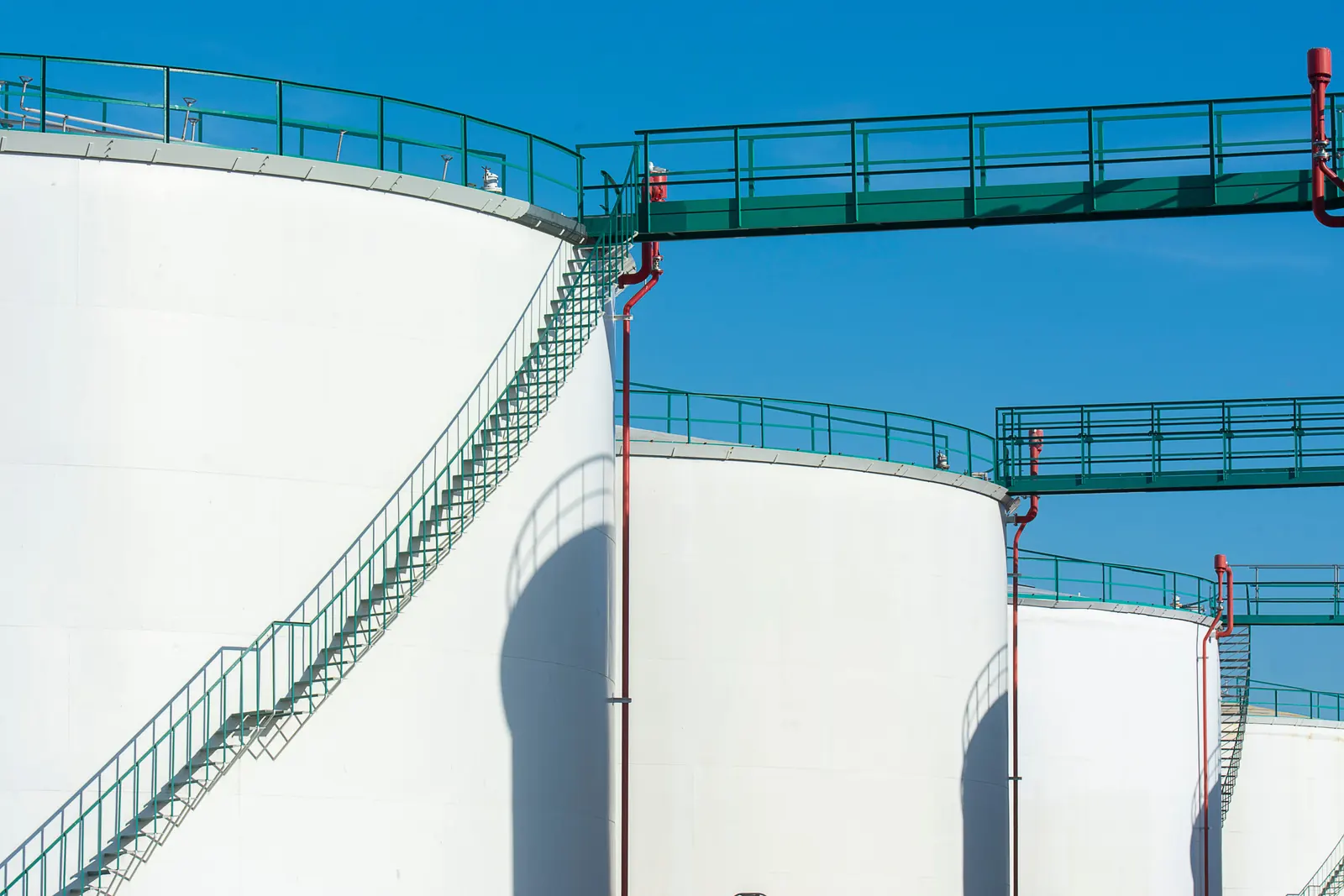 Storage tanks and elevated walkways under a clear blue sky